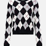 The Antoni Cashmere Argyle Sweater by LISA YANG is crafted from luxurious cashmere and features a classic black, white, and gray argyle pattern with thin red lines. It is displayed against a plain white background.