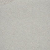 A close-up of the Cambrie Crewneck Sweater by LISA YANG showcases its light beige knit fabric, ribbed crew neckline, and a white inside-collar label featuring the LISA YANG brand in black text, all reflecting a Scandinavian aesthetic.
