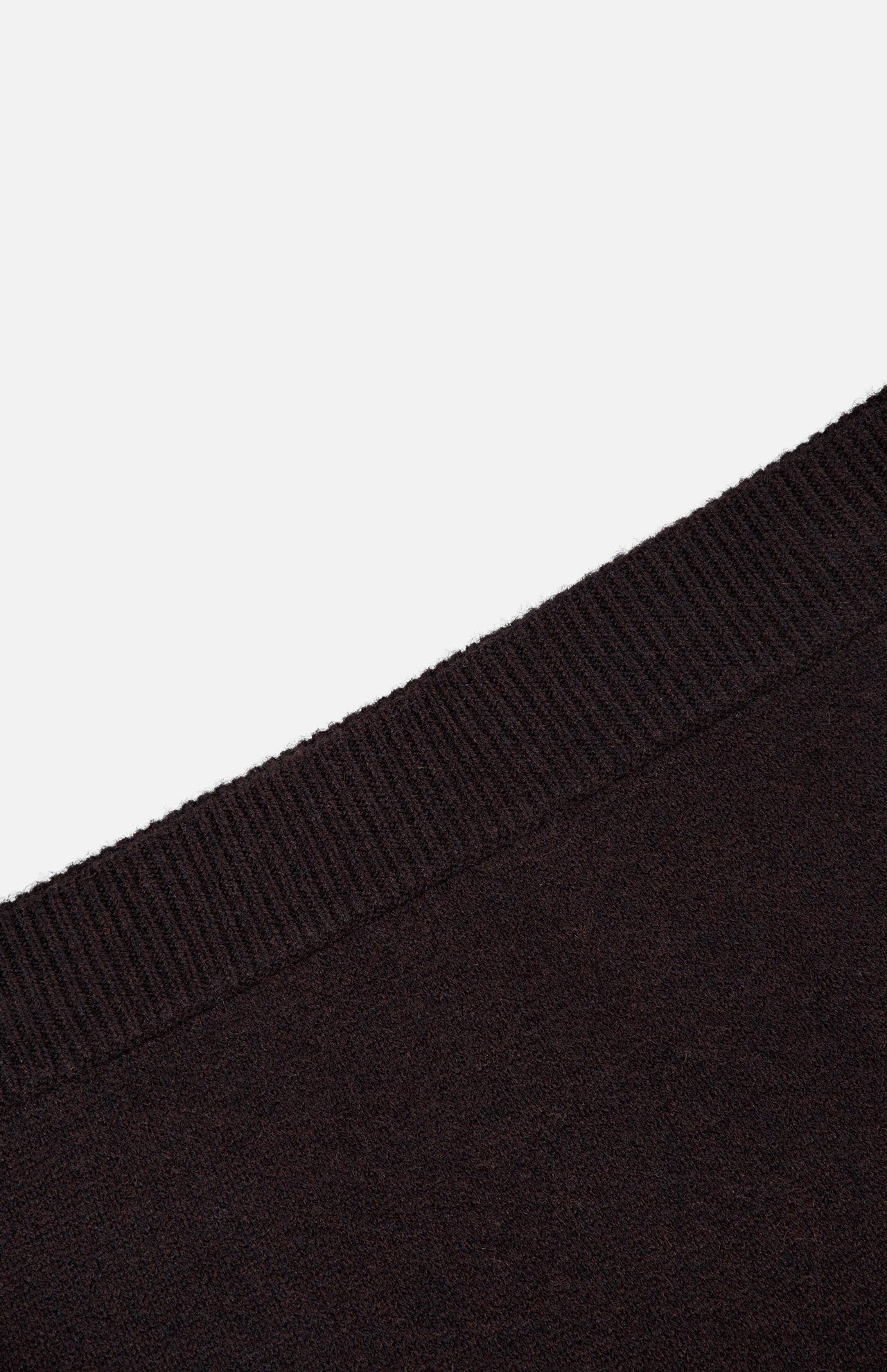 Close-up view of the LISA YANG Clare Cashmere Mini Skirt in black, highlighting the ribbed waistband and fine texture of the heavy knit cashmere fabric, angled diagonally across a white background.