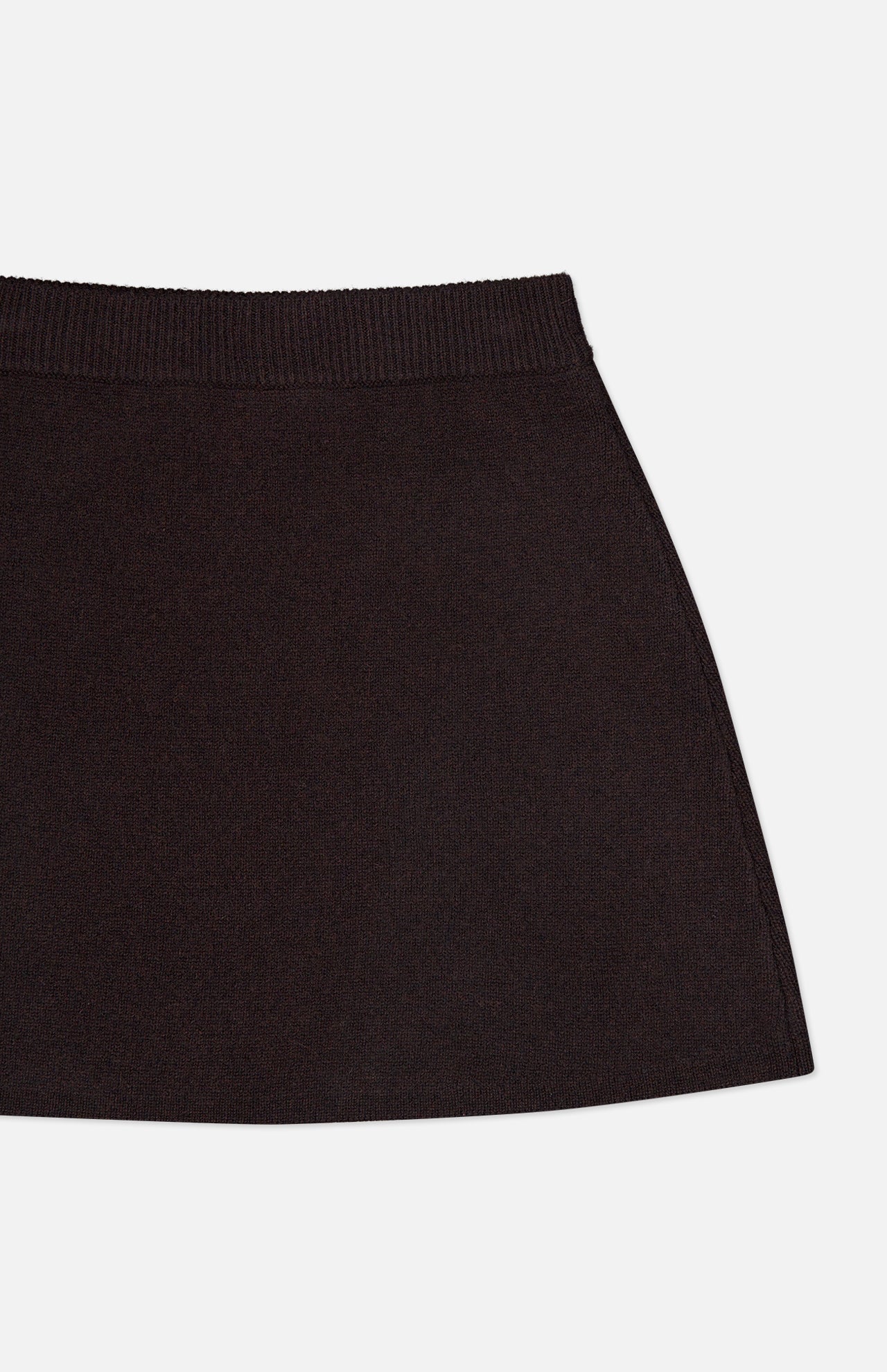 A close-up of the Clare Cashmere Mini Skirt by LISA YANG shows only the upper portion of this slow luxury brand piece, highlighting its ribbed waistband and heavy knit black cashmere against a white background.