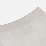 Close-up of the neckline of a light beige knit sweater, featuring ribbed trim detail against a plain white background—a perfect match for the LISA YANG Dolly Cashmere Maxi Skirt in light grey, creating an effortlessly refined look.