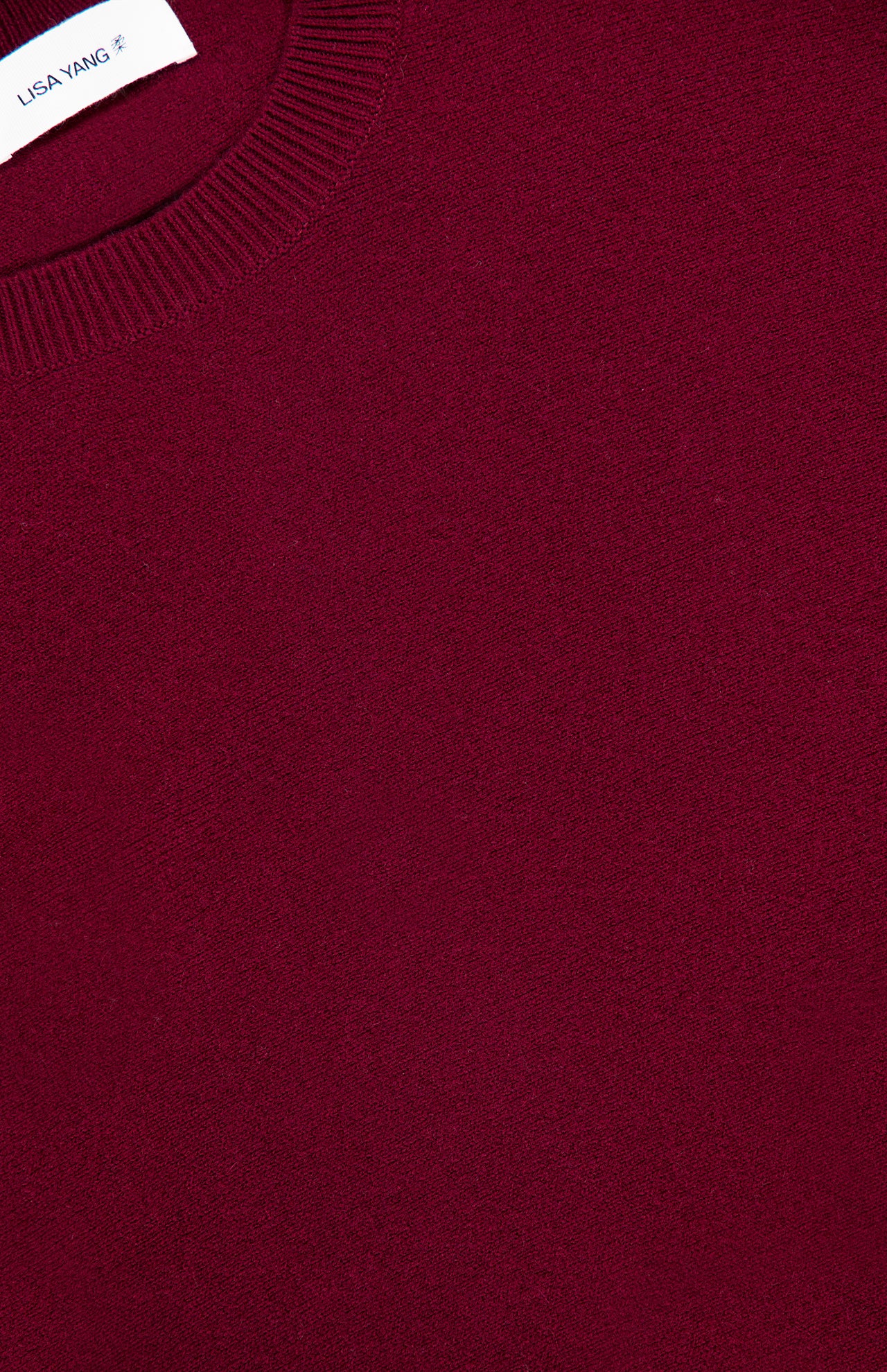Close-up of the Hally Cashmere Sweater in burgundy, featuring a ribbed crew neckline and a small white LISA YANG label sewn inside the collar, exemplifying slow luxury craftsmanship in pure cashmere.