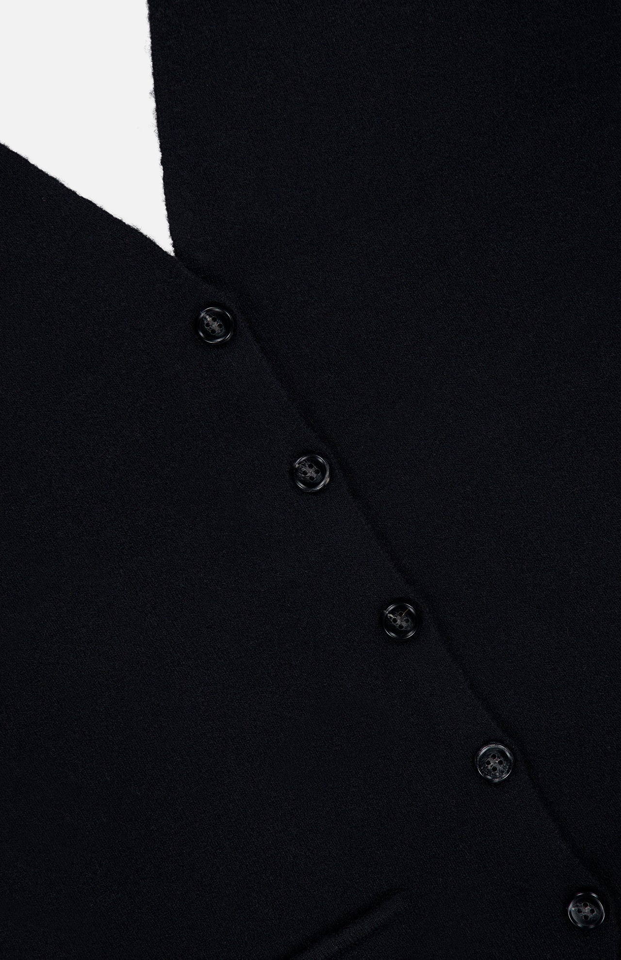 Close-up of the Immy Halter Top in black cashmere from LISA YANG, featuring five sleek black buttons arranged vertically and a partial view of a bottom pocket—a timeless piece from this slow luxury brand.