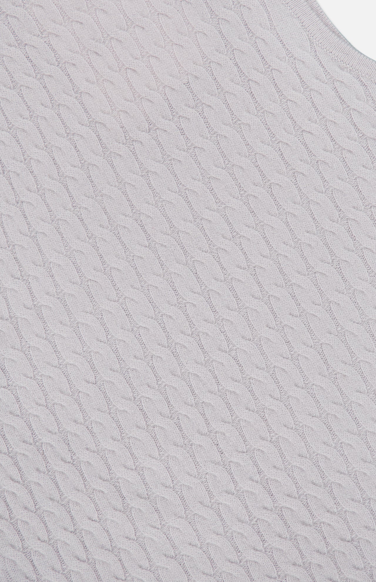 Close-up of the Lora Cashmere Tank Top by LISA YANG, showcasing its light gray cableknit cashmere fabric with a repeating twisted cable pattern viewed at an angle. The texture appears soft and slightly raised, evoking the cozy feel typical of luxury knitwear.