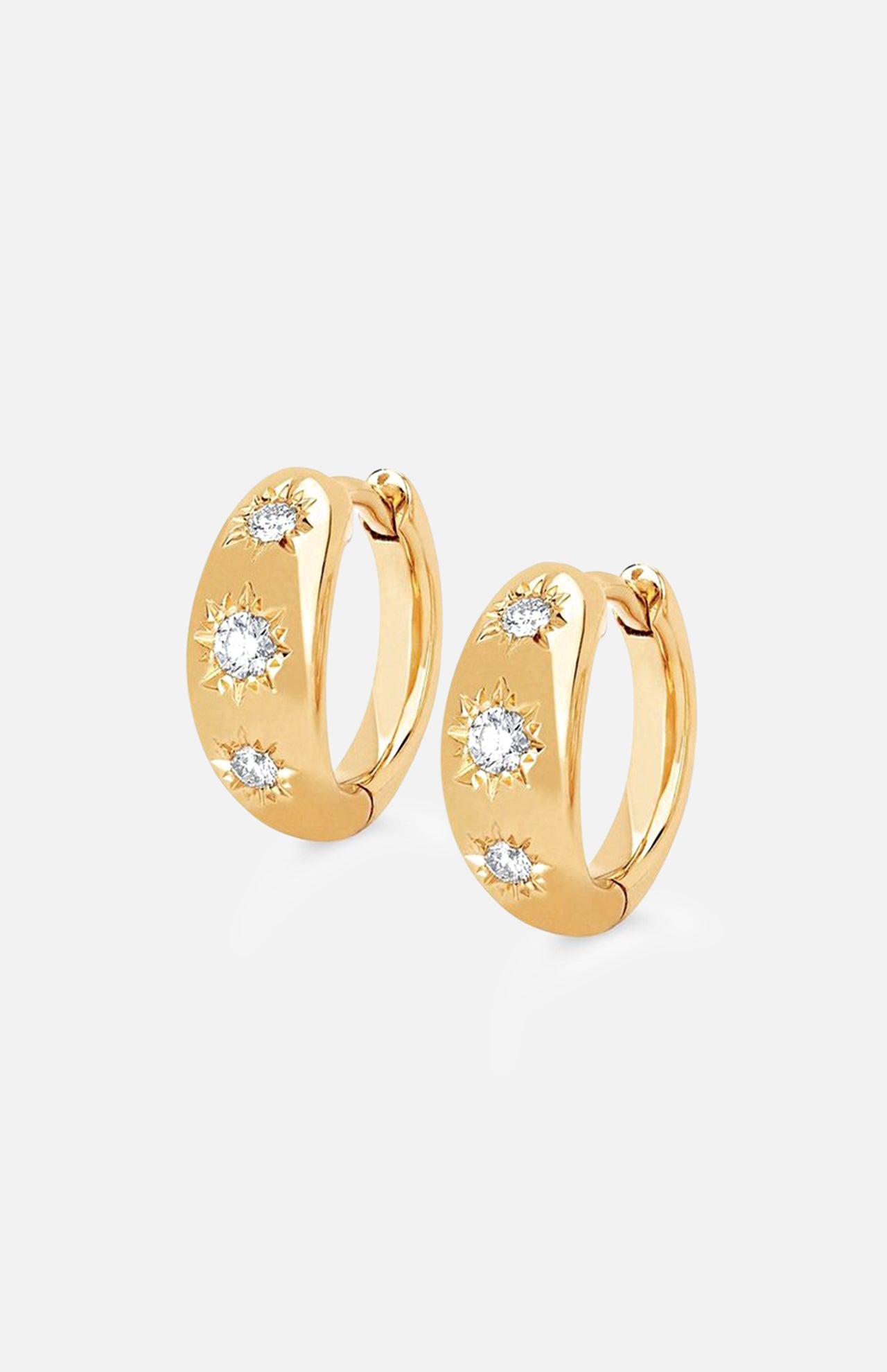The LOGAN HOLLOWELL Three Star Set Rounded Diamond Huggie Earrings feature 14k gold hoops with three round diamonds in starburst patterns, a polished finish, and secure hinged closures.