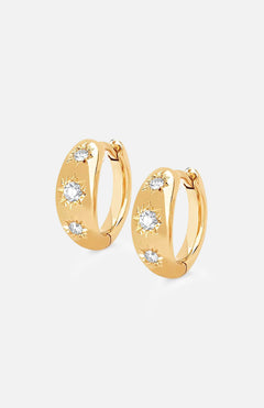 The LOGAN HOLLOWELL Three Star Set Rounded Diamond Huggie Earrings feature 14k gold hoops with three round diamonds in starburst patterns, a polished finish, and secure hinged closures.