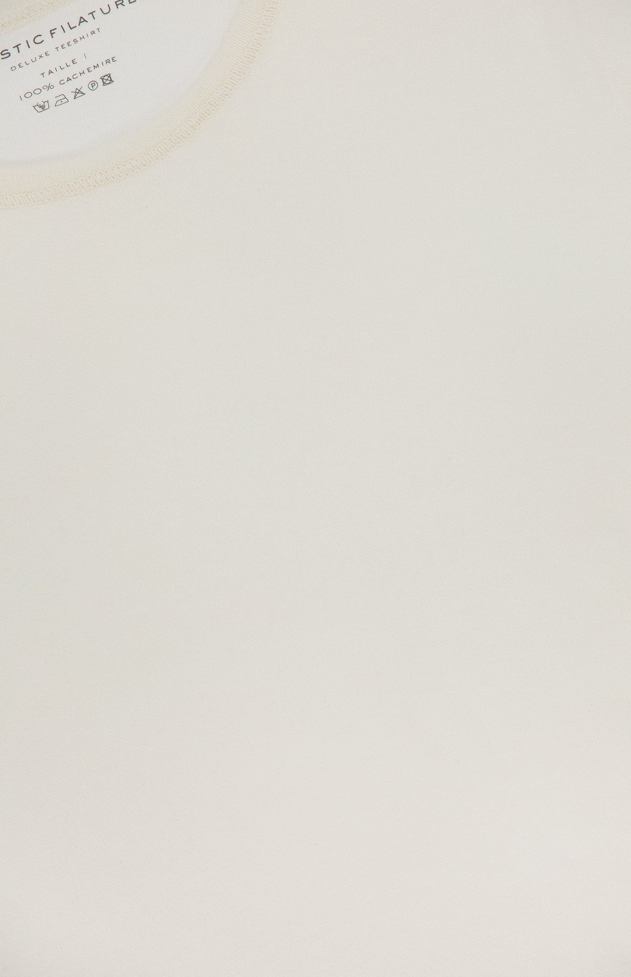 Close-up of a MAJESTIC FILATURES Cashmere Long Sleeve Crewneck T-Shirt in off-white cotton and cashmere. The neck label shows brand details and care instructions in light blue and gray, and notes it's made in Italy.