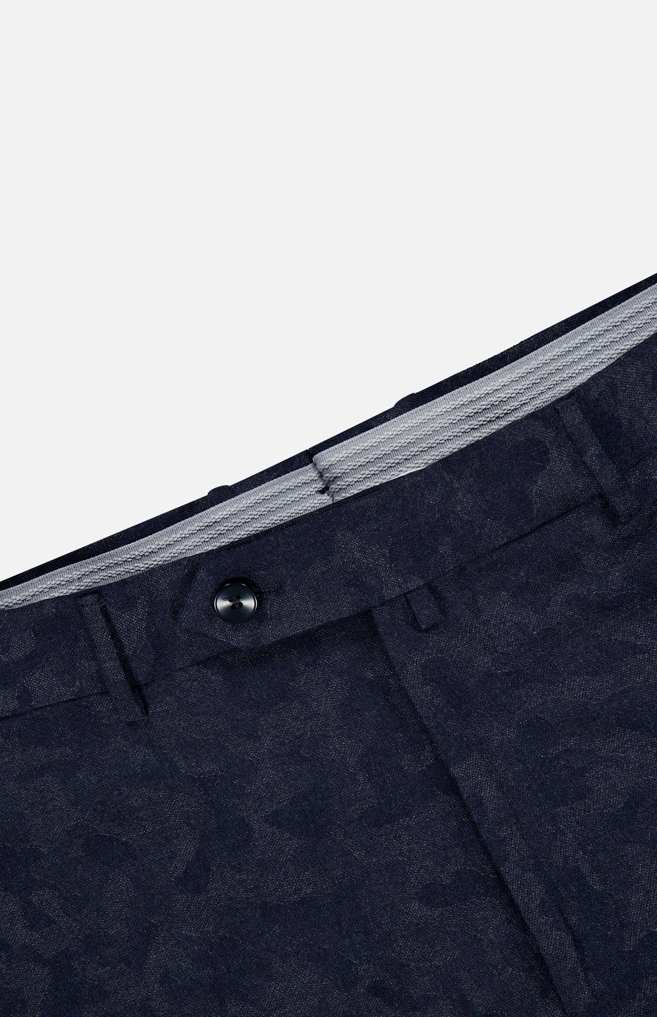 Close-up of the waistband of Malcom’s Wool Cashmere Camo Trouser Pant in dark blue patterned fabric, featuring a black button, belt loops, and a partially visible gray striped inner lining. Expertly crafted in Italy from luxurious wool cashmere.