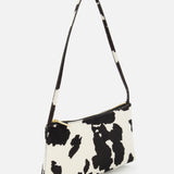 The MANSUR GAVRIEL Gaia Cow Print Shoulder Bag, featuring a black and white pattern, gold zipper closure, and matching strap, is displayed against a white background.