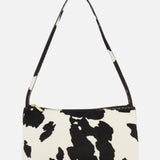 The Gaia Cow Print Shoulder Bag by MANSUR GAVRIEL is a small rectangular black and white handbag with a single strap and bold animal print, shown on a plain white background.