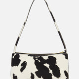 The Gaia Cow Print Shoulder Bag by MANSUR GAVRIEL features a bold black and white cow pattern, a short strap, and a zippered top closure, shown against a plain white background.