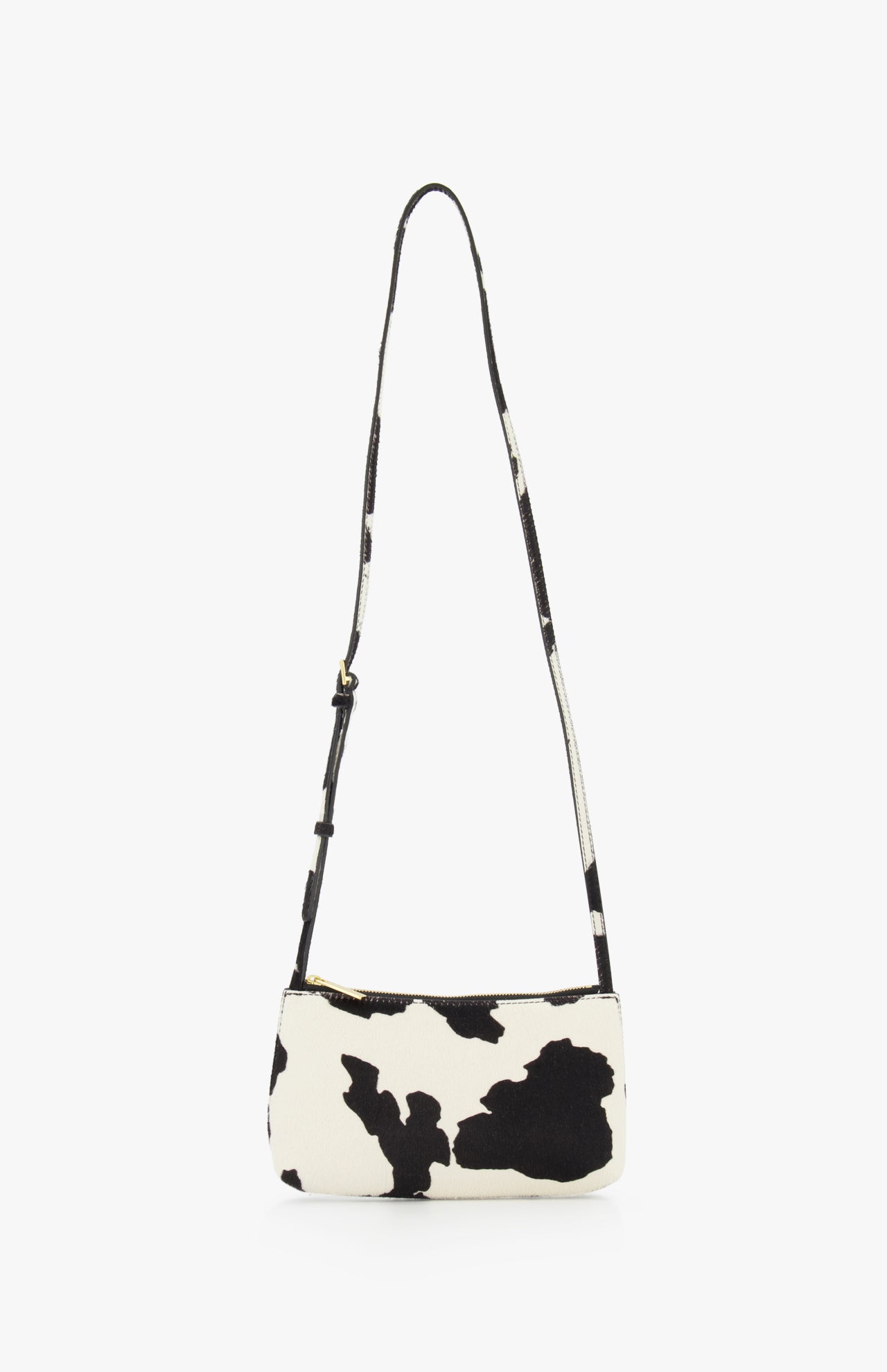 The MANSUR GAVRIEL Mini Gaia Cow Print Crossbody Bag features a black and white cow pattern, a small rectangular shape, and a long adjustable strap, showcased against a plain white background.