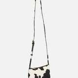 The MANSUR GAVRIEL Mini Gaia Cow Print Crossbody Bag is a small rectangular purse with a long strap, showcasing a black and white cow print design against a plain white background.
