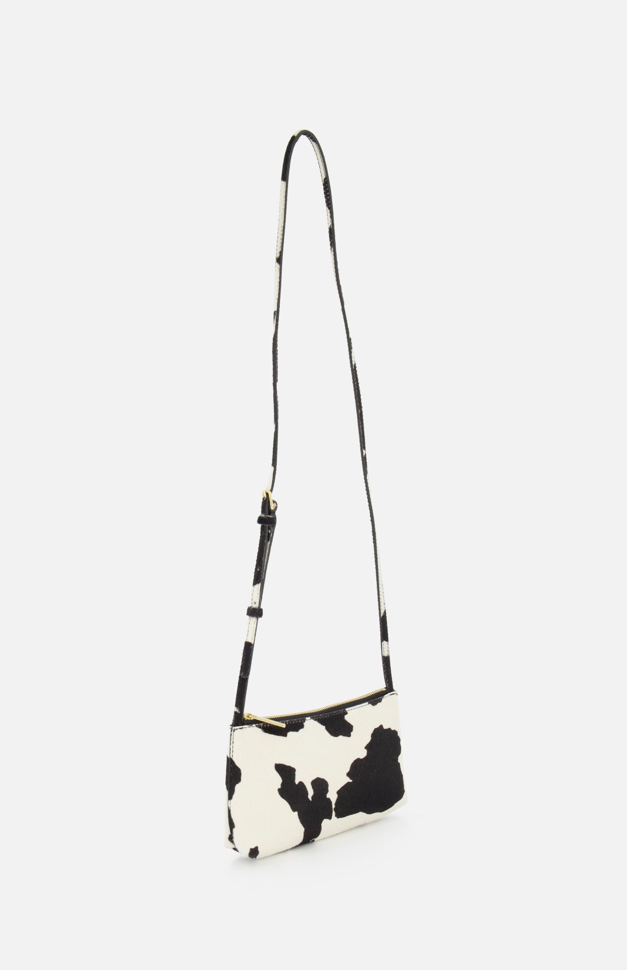 The MANSUR GAVRIEL Mini Gaia Cow Print Crossbody Bag is a small rectangular purse with a long strap, showcasing a black and white cow print design against a plain white background.
