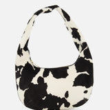 The MANSUR GAVRIEL Mini Gnocchi Cow Print Bag features a black and white animal print, a curved hobo silhouette, and a top zipper closure.