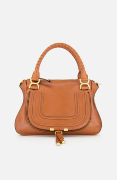 The CHLOÉ Marcie Leather Saddle Bag features gold hardware, double leather-wrapped handles, and a curved front pocket, shown on a plain white background.