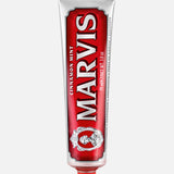A red and silver tube of MARVIS Cinnamon Mint Toothpaste stands upright with a red cap, showcasing ornate design elements and bold white text on the front—an Italian luxury toothpaste that offers a uniquely refreshing cinnamon mint flavor.
