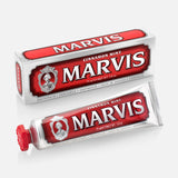 A box and tube of MARVIS Cinnamon Mint Toothpaste are displayed, featuring red and white luxury Italian packaging with bold text and a vintage-style logo that includes a portrait.