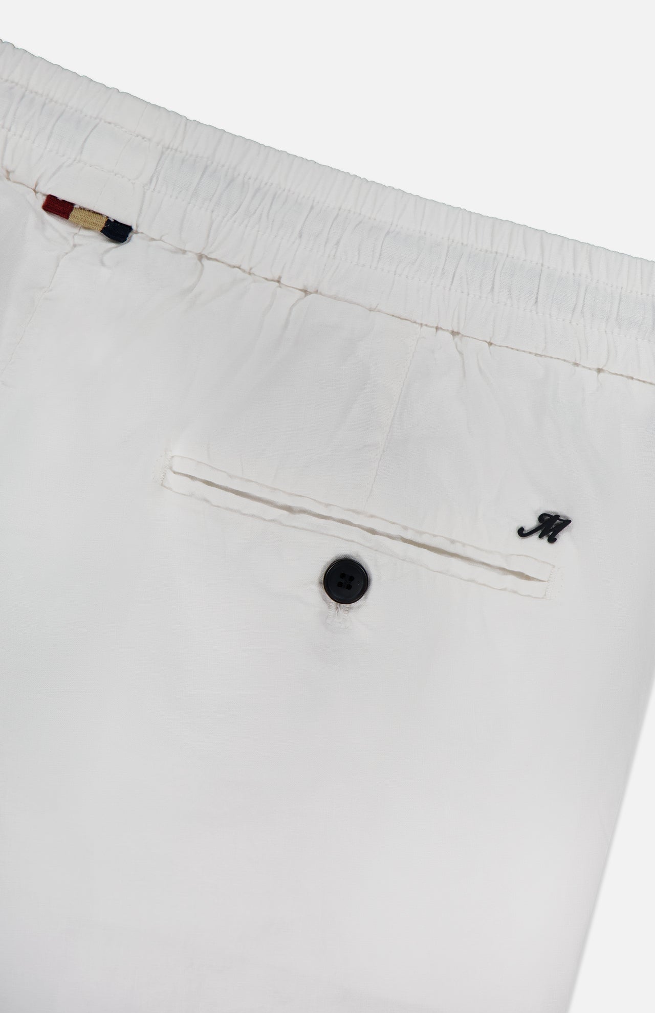 Close-up of MASON'S Linen Cotton NY Sack Drawstring Trouser Pant in white, featuring an elastic waistband, back pocket with black button, small black embroidered M, and red-white-blue striped fabric tag near the waistband.