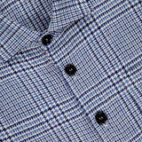 Close-up of the MAURIZIO BALDASSARI Classic Pockets Plaid Overshirt in blue and white, showcasing a micro houndstooth checkered pattern, black buttons, and a “Made in Italy” tag. Expertly crafted from a premium hemp wool blend, this elevated overshirt combines refined texture with classic style.