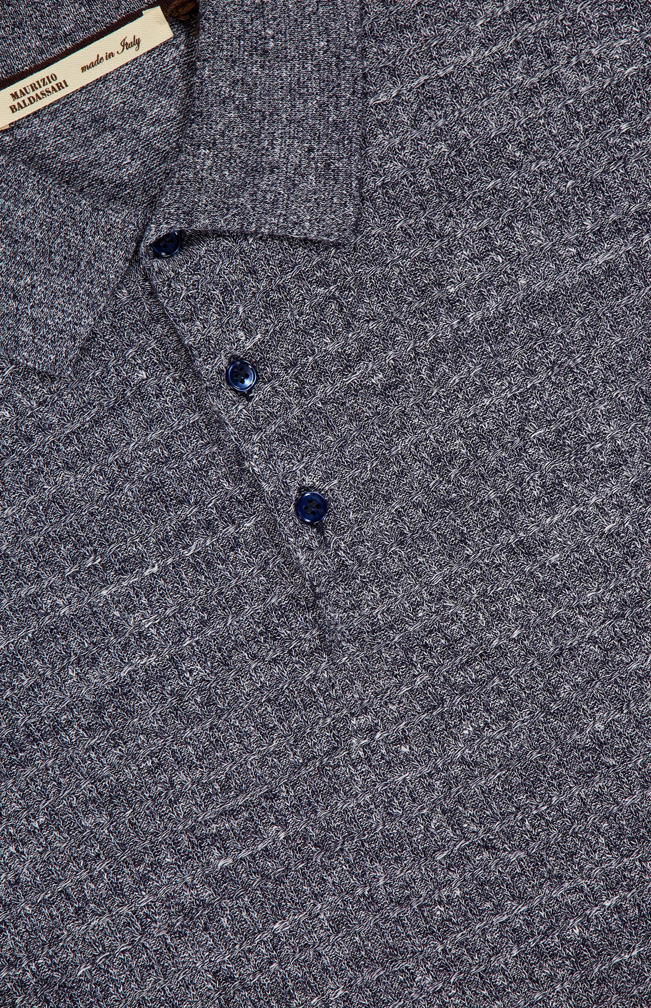 Close-up of the MAURIZIO BALDASSARI Front Stitch 3B Polo Shirt in textured gray linen-blend, featuring three dark buttons and a visible “Made in Italy” label near the collar.