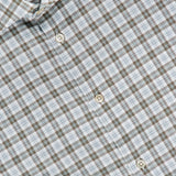 A close-up of the Santini Spread Collar Dress Shirt by MAURIZIO BALDASSARI, featuring a light blue, brown, and white plaid cotton fabric. This expertly crafted Italian shirt showcases a visible spread collar and crisp white buttons.