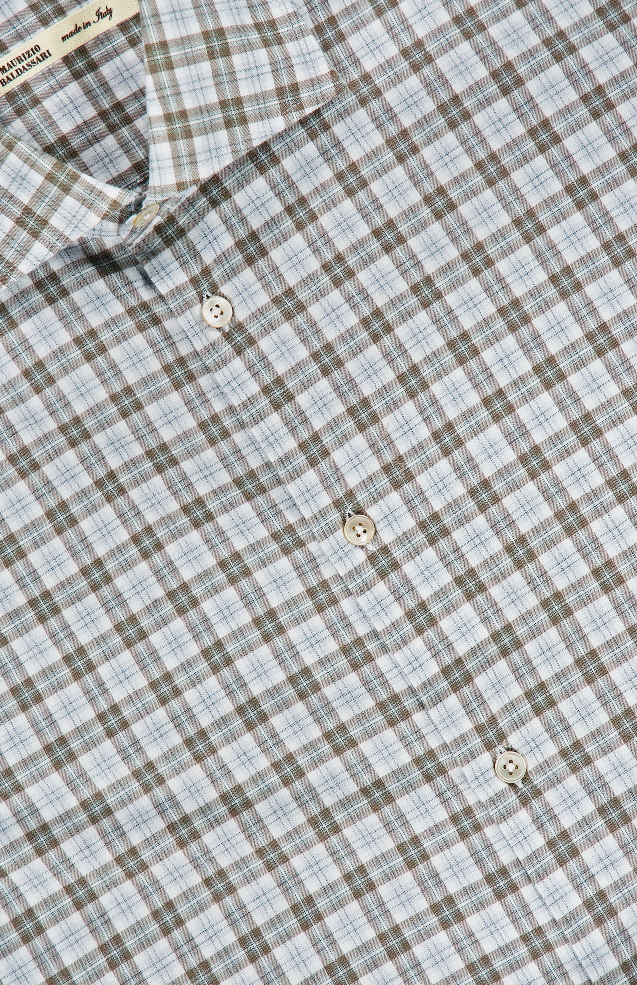 A close-up of the Santini Spread Collar Dress Shirt by MAURIZIO BALDASSARI, featuring a light blue, brown, and white plaid cotton fabric. This expertly crafted Italian shirt showcases a visible spread collar and crisp white buttons.