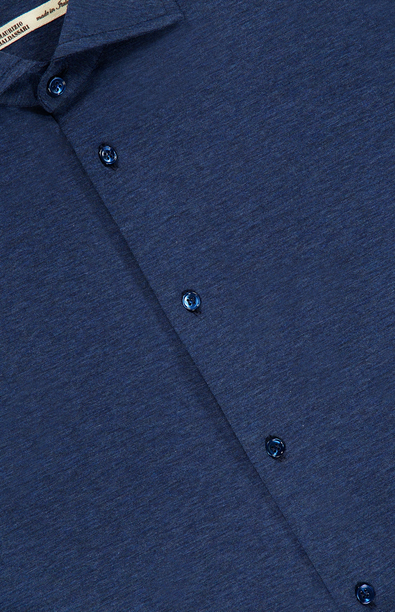 Close-up of the Santini Spread Collar Shirt by MAURIZIO BALDASSARI, featuring its refined collar, buttons, and textured blue fabric—ideal for smart casual settings. A label in the top left corner indicates this stylish navy shirt is crafted in Italy.
