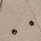 Close-up of the Cashmere Button Sleeve Cape Jacket by MAX MARA in beige, showcasing its double-breasted silhouette with two brown buttons and a partial view of the collar. The soft, textured cashmere fabric adds to its luxurious appearance.