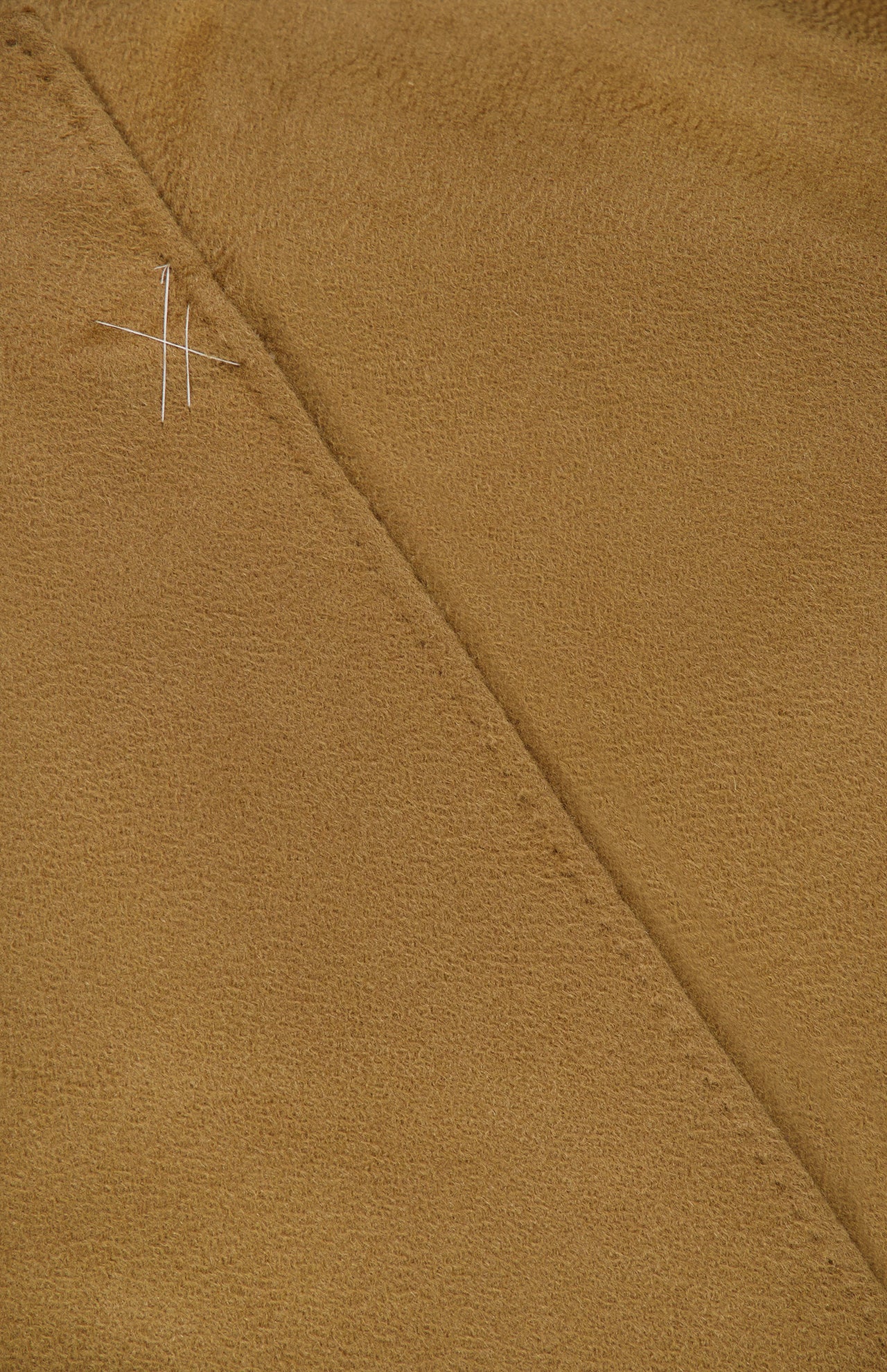 Close-up of light brown suede fabric from the MAX MARA Cashmere Trench Coat, showing a diagonal seam and visible white basting stitches near the top left corner.