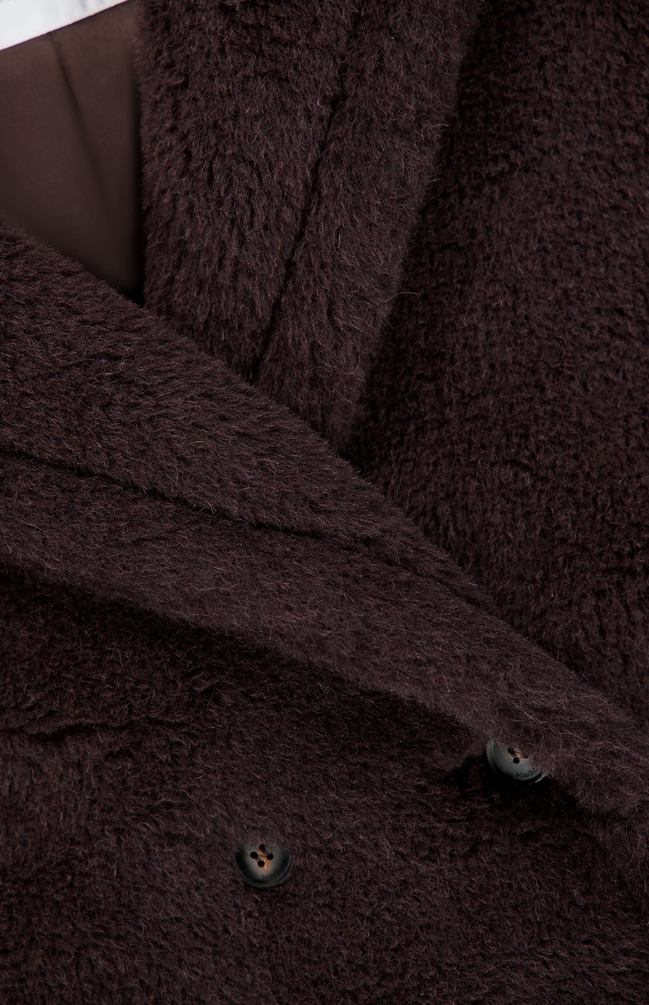 Close-up of a MAX MARA Long Teddy Coat, featuring a dark brown fuzzy texture with a double-breasted front and two visible buttons.