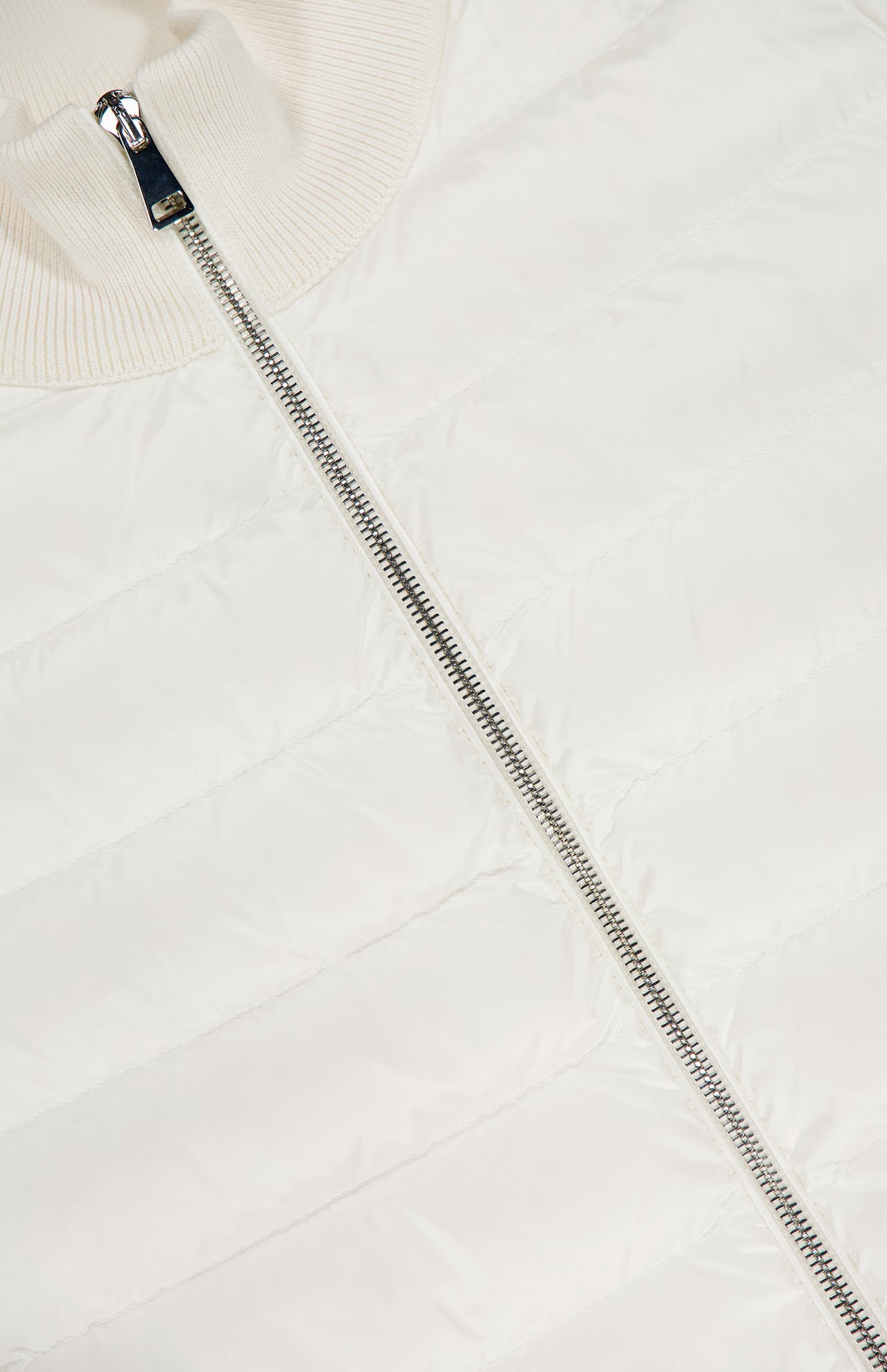 Close-up of the MONCLER Down Filled Cardigan Jacket in white, featuring horizontal quilting, a shinysilver center zipper, and a ribbed collar.