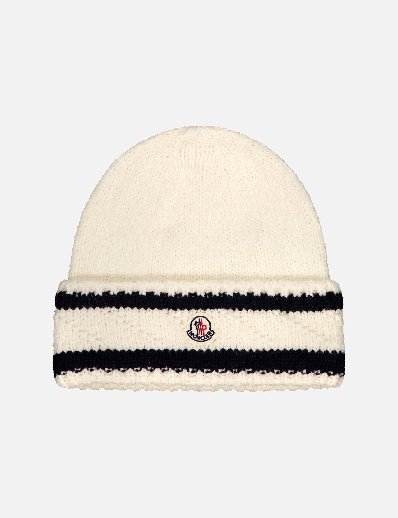 The MONCLER Striped Beanie Hat is a cream knit wool design with two black horizontal stripes and a small embroidered logo patch on the front cuff, shown against a light background.