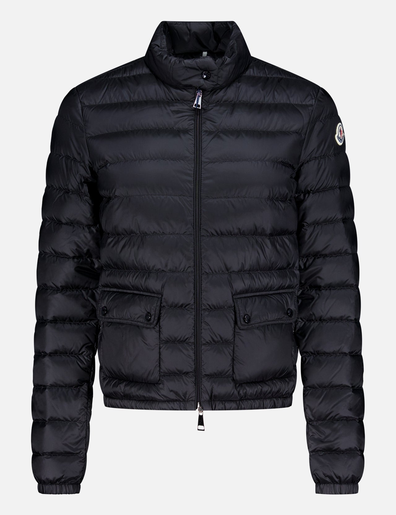 The MONCLER Lans Jacket is a black puffer with après ski style, horizontal quilting, front zip, flap button pockets, high collar, fitted waist and cuffs, and a small logo patch on the upper left sleeve.