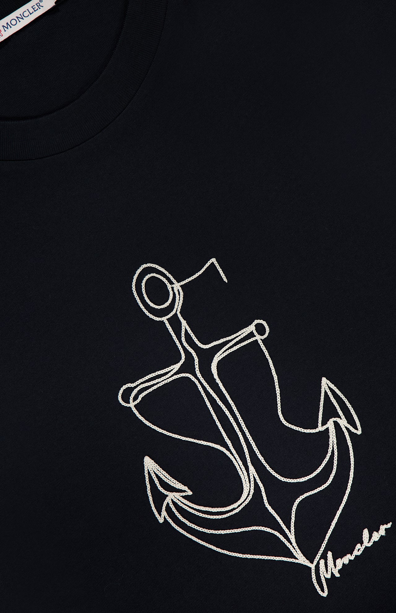 Close-up of the MONCLER Anchor Graphic Short Sleeve T-shirt in black, featuring a white embroidered anchor and monogram at the bottom right—an ideal pick for fans of nautical-inspired designer tees.