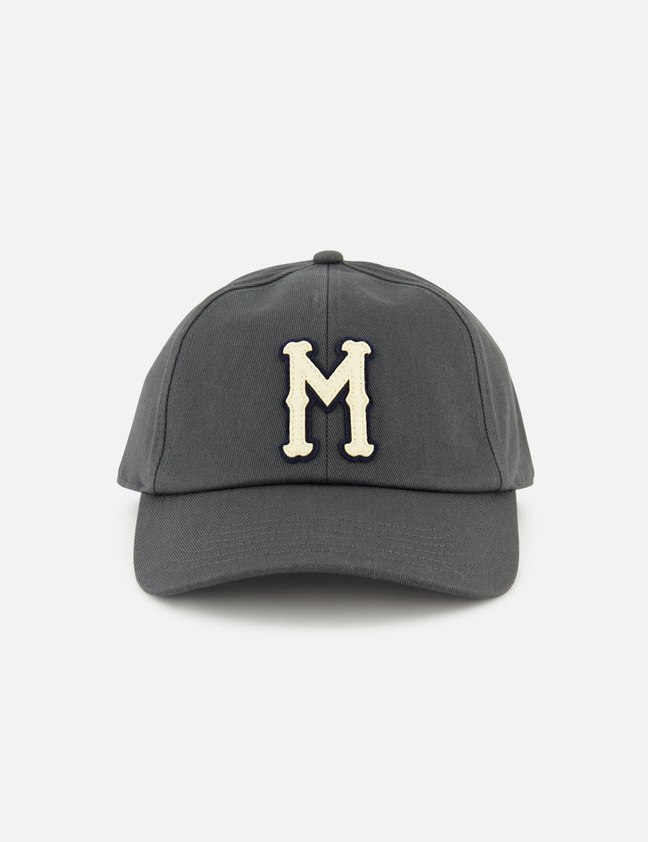 The MONCLER Monogram Baseball Cap features a grey design with a cream-colored embroidered letter M on the front, inspired by designer outerwear style, and is shown against a plain white background.