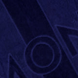 Close-up of the MONCLER Logo Beach Towel showing its textured dark blue surface, with bold raised and indented lettering—like "M" and "O"—and vertical stripe patterns.