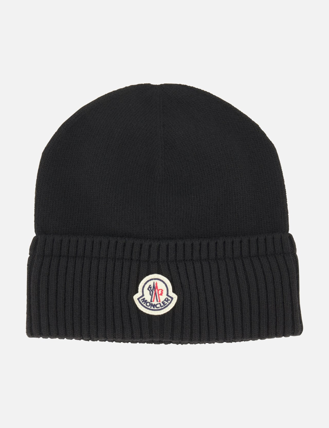 The MONCLER Ribbed Logo Beanie is a black knit wool hat with a ribbed texture and folded brim, featuring the brand’s signature logo patch on the front center.