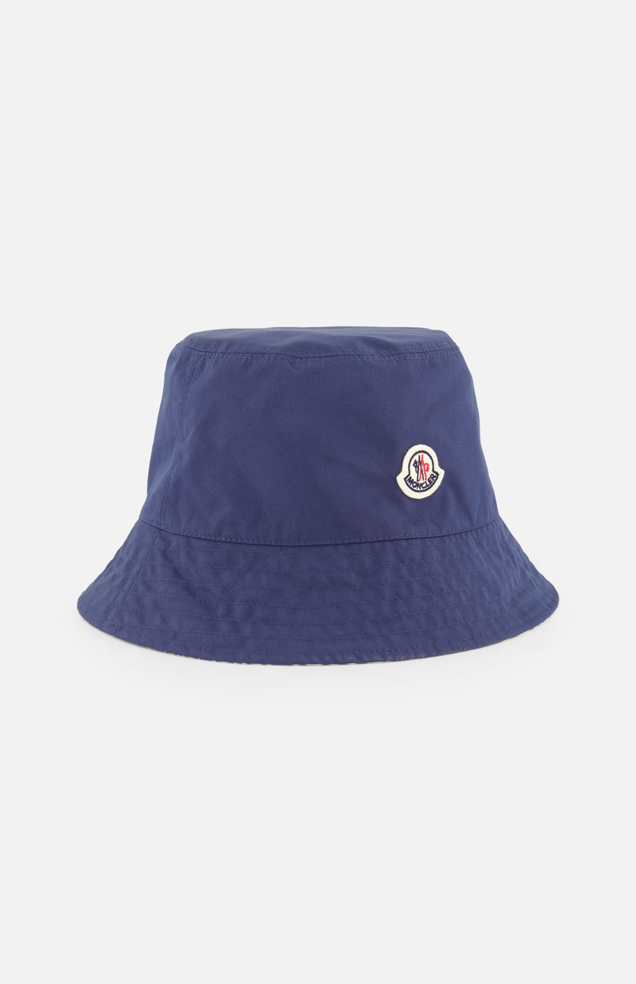 The MONCLER Reversible Bucket Hat in plain navy blue features a small front logo patch, is crafted from cotton, and is shown against a white background.