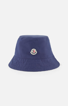 A MONCLER Reversible Bucket Hat in navy blue, crafted from premium cotton with a small embroidered logo patch on the front, is shown against a plain white background.