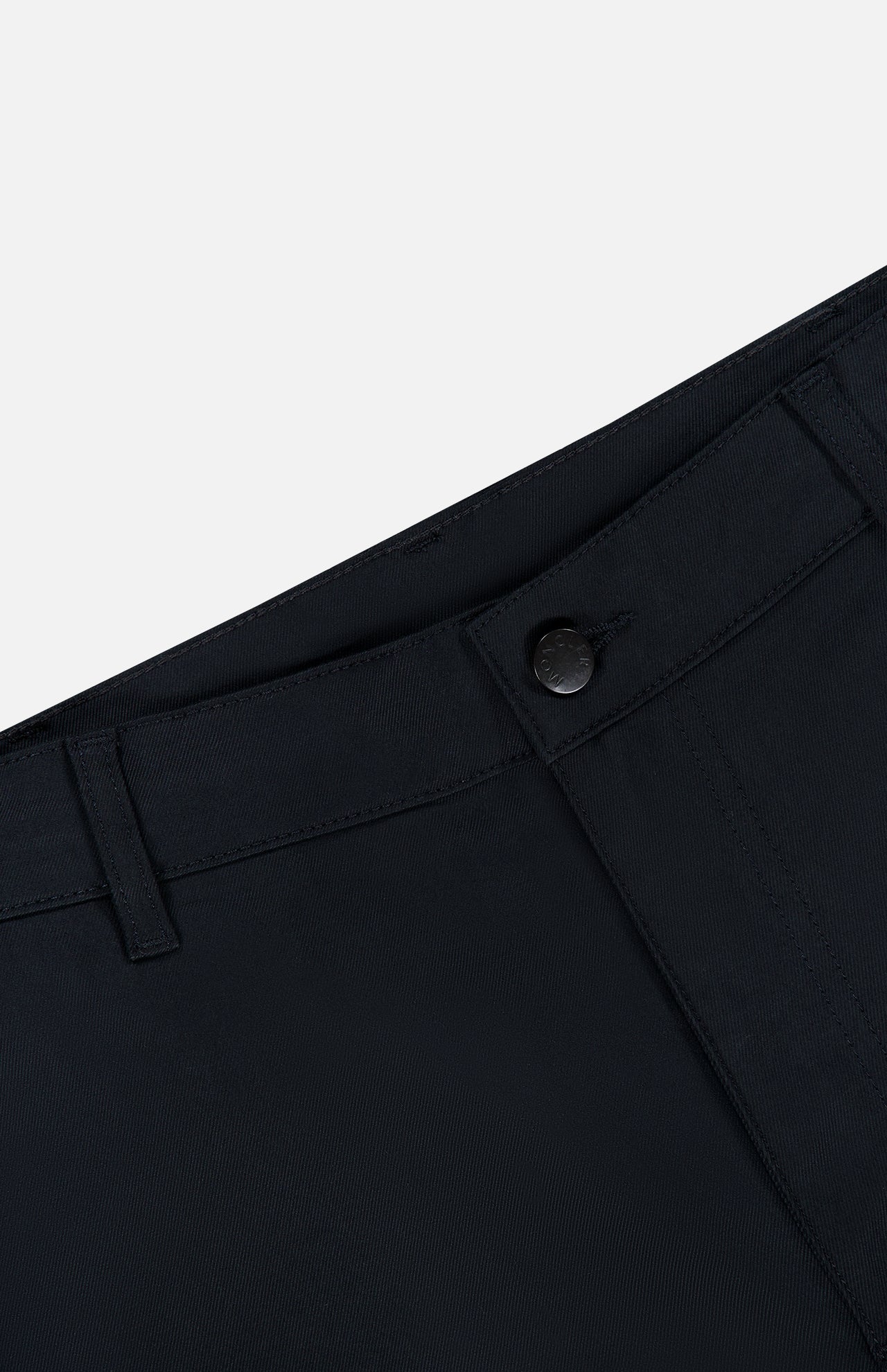 Close-up of the waistband and top front section of the MONCLER Zip Pocket Stretch Pant in black, featuring a button closure, belt loops, and visible stitching against a light gray background.