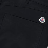 Close-up of the MONCLER Zip Pocket Stretch Pant in black, showcasing a sleek zip pocket topped with a subtle Moncler logo patch. Visible stitching and belt loops emphasize the structure and refined details of this stretch outerwear piece.
