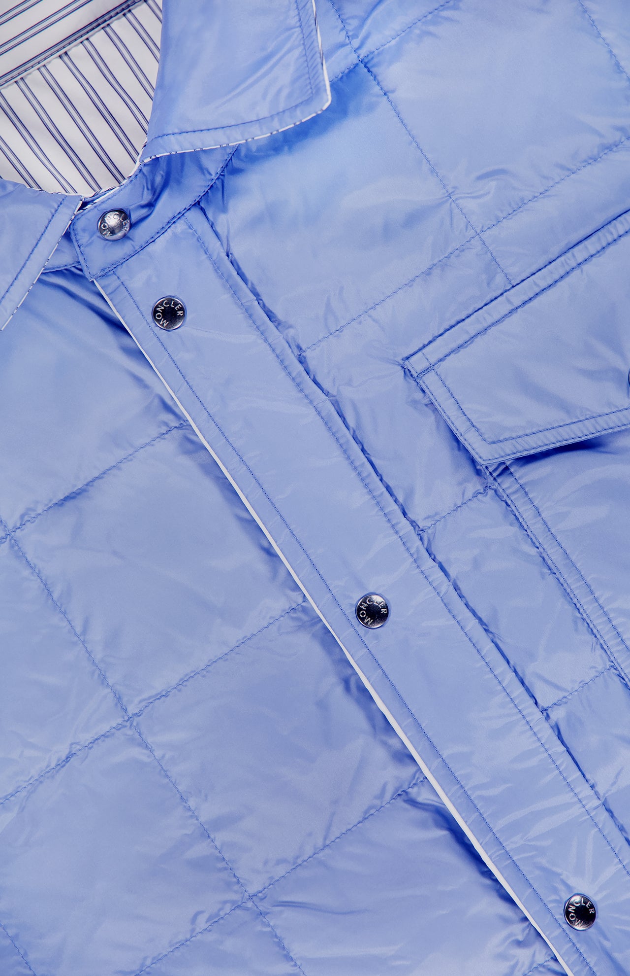 Close-up of the MONCLER Reversible Crescent Shirt Jacket in light blue, featuring silver snap buttons, a chest pocket, and white-and-blue striped inner collar—an elevated men’s outerwear piece.