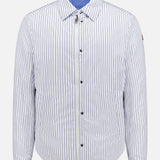 The MONCLER Reversible Crescent Shirt Jacket for men features light blue and white vertical stripes, a collar, long sleeves, front zipper, snap buttons, light blue lining, and a relaxed fit—ideal for stylish outerwear.