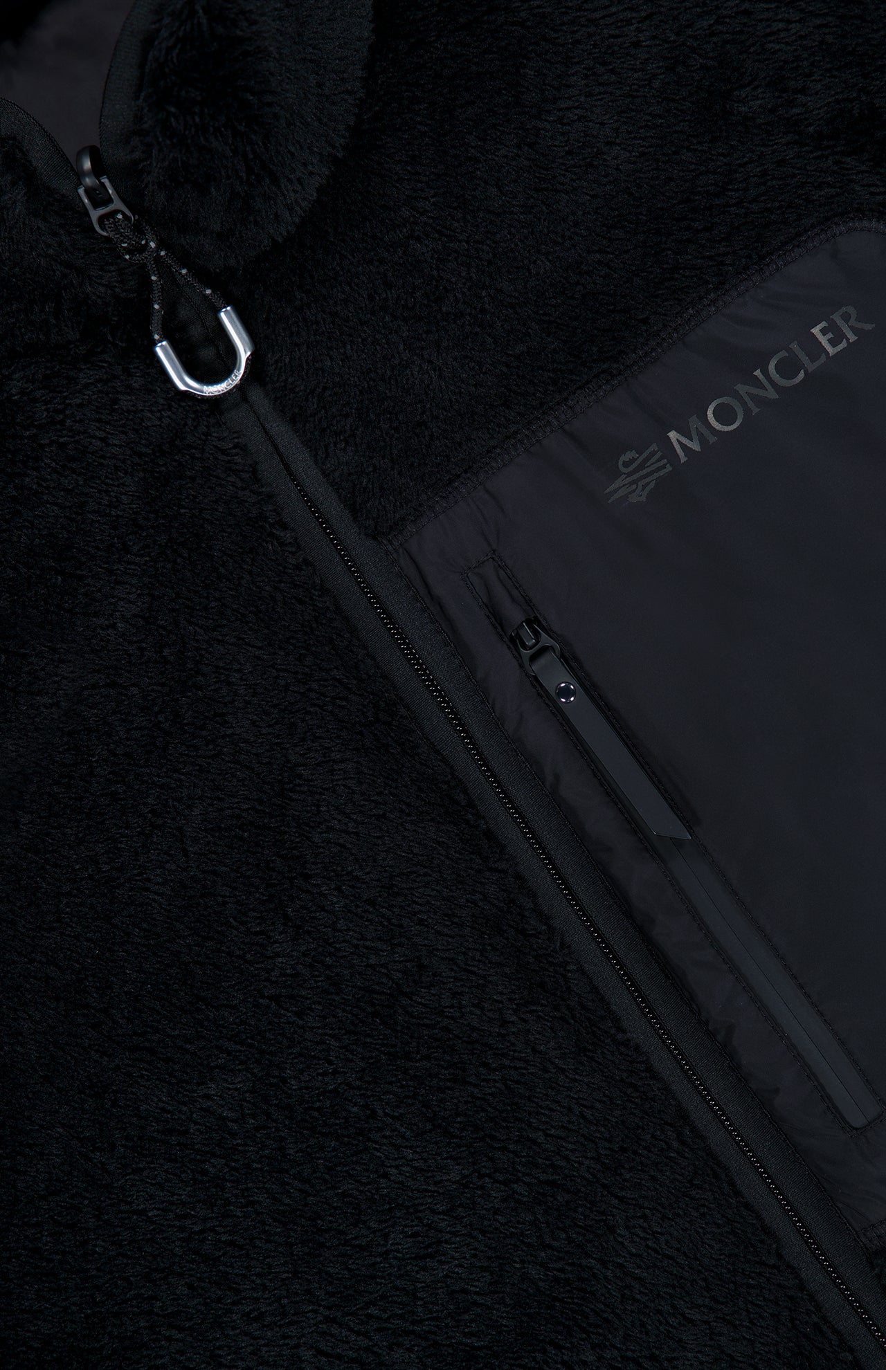 Close-up of the Fleeced Chest Pocket Vest by MONCLER, a black cold-weather essential featuring a zipper, a carabiner on the collar, and a zippered chest pocket adorned with the MONCLER logo in white letters.