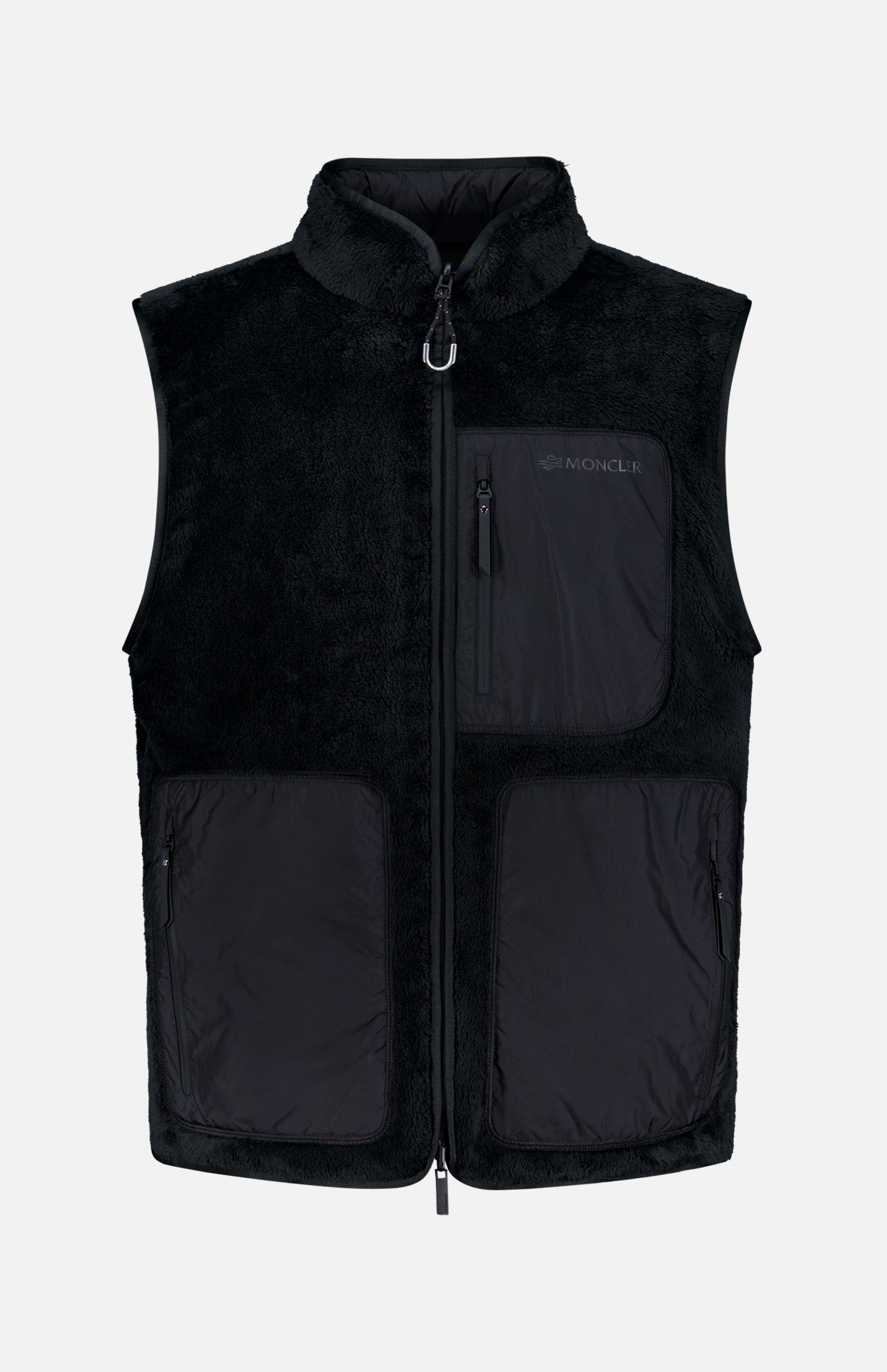 Certainly! Here’s a rewritten version of the sentence using your product data: The MONCLER Fleeced Chest Pocket Vest is a sleek black fleece vest featuring a high collar, front zipper, and three spacious black zippered pockets on the front. The signature Moncler logo is displayed on the left chest pocket. Designed as a dependable cold-weather essential, it stands out against a plain white background.