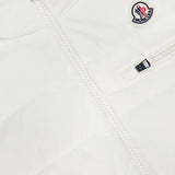 Close-up of the MONCLER Gienah Houndstooth Reversible Vest in white, featuring a visible zipper, small chest zip pocket, Moncler logo patch on the upper left, and smooth quilted fabric.