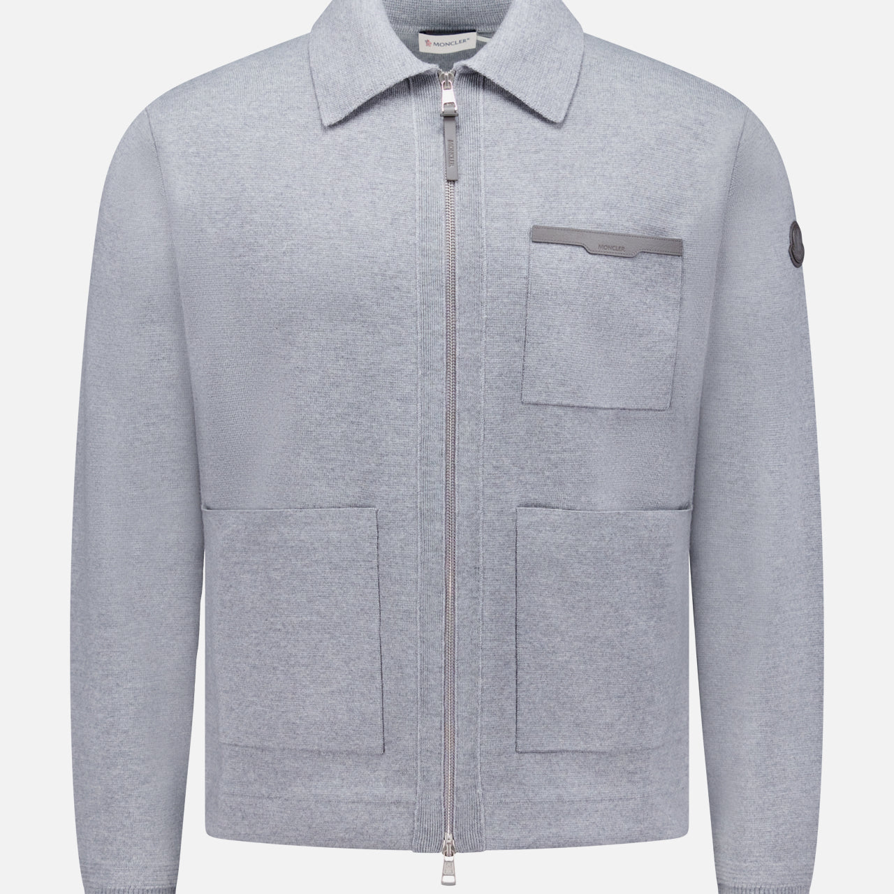 The MONCLER Knit Zip Up Overshirt features a light grey color, collar, two large front pockets, a chest pocket with flap, and a small left sleeve patch—crafted from soft textured fabric for stylish transitional wear.
