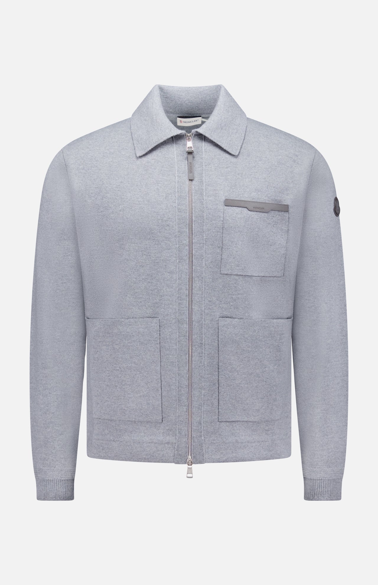 The MONCLER Knit Zip Up Overshirt features a light grey color, collar, two large front pockets, a chest pocket with flap, and a small left sleeve patch—crafted from soft textured fabric for stylish transitional wear.