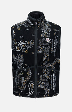 The MONCLER Reversible Paisley Fleece Vest features a black, white, and tan paisley pattern in a sleeveless teddy fleece design. It includes a front zipper closure, high collar, two large front pockets, and is finished with the Moncler logo patch on the left chest. Offering both style and versatility, this standout vest can be worn on either side.